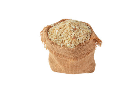 Brown rice grain in the jute canvas sack isolated on white. Uncooked,raw, whole grain cereal.の写真素材