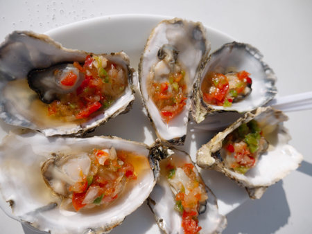 Steamed oysters with vegetables and vinegar in the shells. Gourmet seafood plate.の写真素材