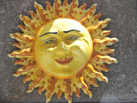 Handmade ceramic yellow symbolic sun of SICILY on wall in city center of TAORMINA with smile and rays in 2016 warm sunny day in Italy, Europe on May.の写真素材