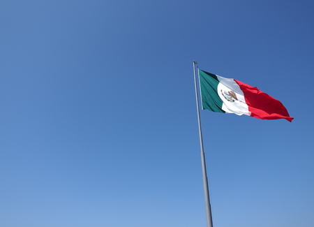 National mexican flag on mast on clear blue sky on beach at Acapulco city in Mexico in 2018 warm sunny winter day, North America on March.の写真素材