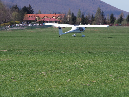 BIELSKO-BIALA, POLAND on APRIL 2018: Scenery with white Pipistrel Virus SW airplane on grassy airfield, taxiing to takeoff, belongs to air club in european city in warm sunny spring day.のeditorial素材