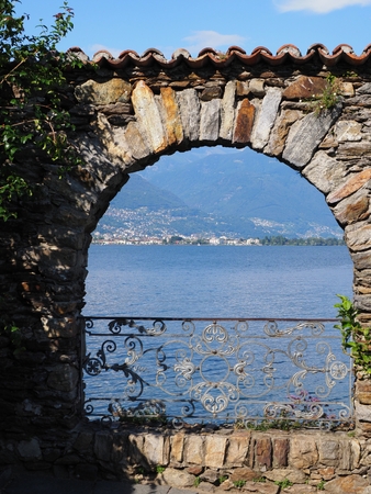 Stony arch at alpine Brissago island in Switzerland with swiss Lake Maggiore and Alps mountains landscapes near european Ascona city in 2017 warm sunny summer day on July - vertical.の写真素材
