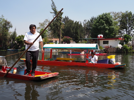 XOCHIMILCO, MEXICO on MARCH 2018: Mexican gondolier on beautiful colored boats with tourists at Floating Gardens in warm sunny winter day.のeditorial素材