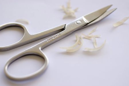 a pair of curved nail scissors and some nail clippingsの写真素材