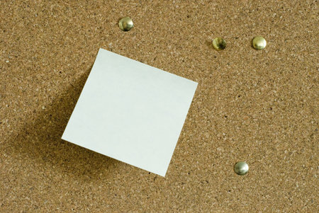 yellow paper sticky note on a cork noticeboard with drawing pins