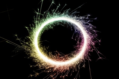 bright multi colored circle of glowing sparks on a black backgroundの写真素材