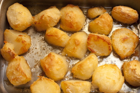 Catering background of delicious golden roast potatoes in a hot roasting pan fresh from the ovenの写真素材