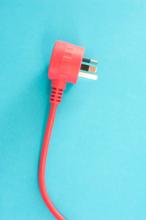 Red integrated electric cable with a three prong Australian plug lying on a blue background with copy space in a power and energy conceptの写真素材