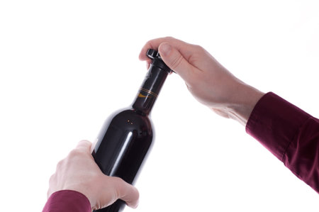 Two hands are cutting the capsule of a red wine bottleの写真素材