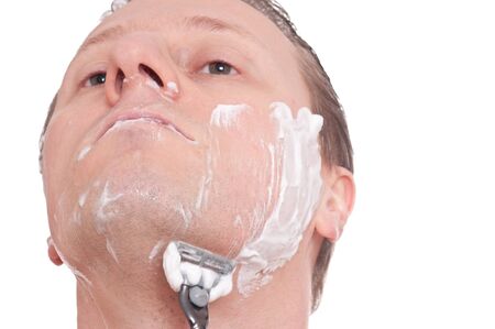 A man is shaving his face with a razorの写真素材