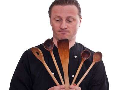 A cook is looking at five cooking spoons in his handsの写真素材