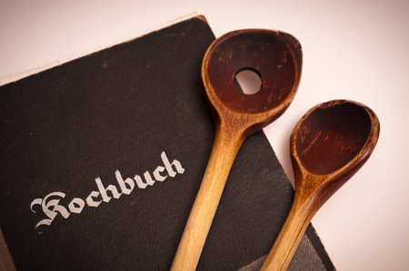 Old cookbook and two wooden cooking spoonsの写真素材