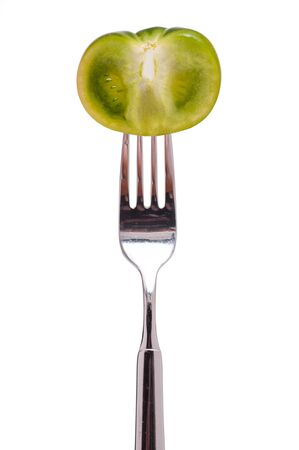 White isolated green tomato on a forkの写真素材