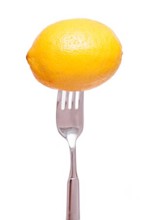 White isolated yellow lemon on a forkの写真素材