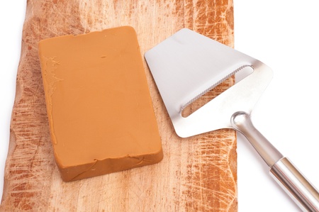 Norwegian Gudbrandsdalen cheese with slicer on a wooden boardの写真素材