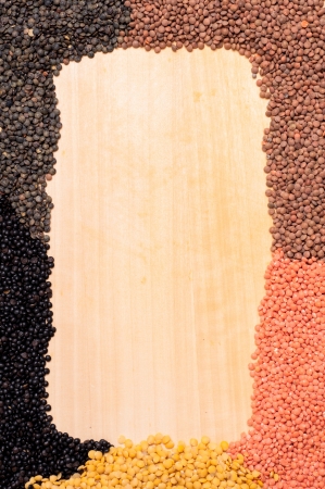 Frame of yellow, red, brown and black lentils on a wooden boardの写真素材