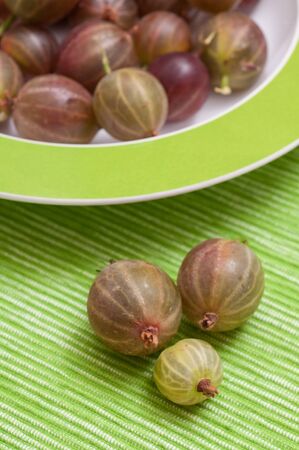 Ripe gooseberries in a green plateの写真素材