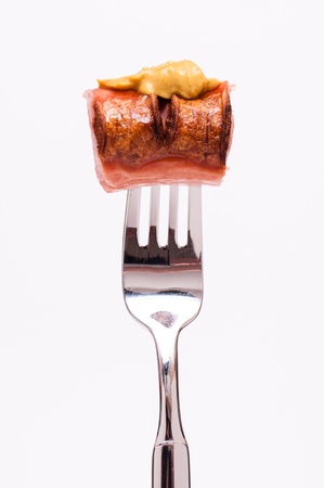 Mustarrd on a smoked polish sausage on a forkの写真素材