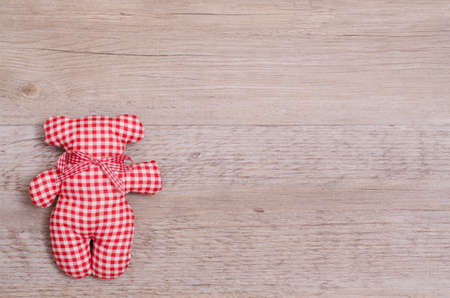 Red and white checkered toy bear on a woodne boardの写真素材