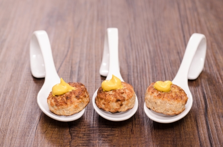 Meatballs with mustard on a white spoon of porcelainの写真素材