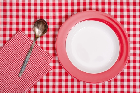 Empty plate with spoon and napkin on red checked table clothの写真素材