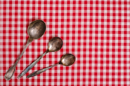 Three silver spoons on a checked table clothの写真素材