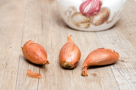 Three shallots on a old weathered wooden boardの写真素材