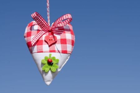 Heart of cloth with bow of ribbon at a blue skyの写真素材