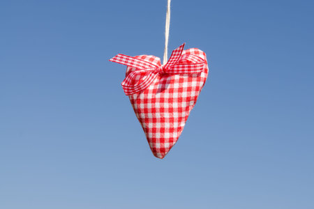 Red white checked heart of cloth with blue skyの写真素材