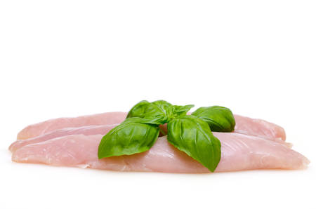Raw turkey meat with green basil on white backgroundの写真素材