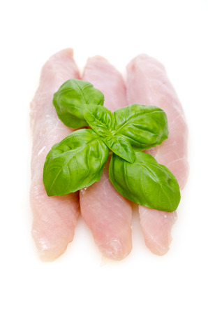 Raw turkey meat with green basil on white background in vertical formatの写真素材