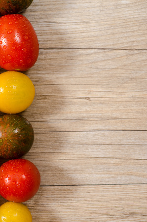 Old wood with red, green and yellow tomatoes on the edgeの写真素材