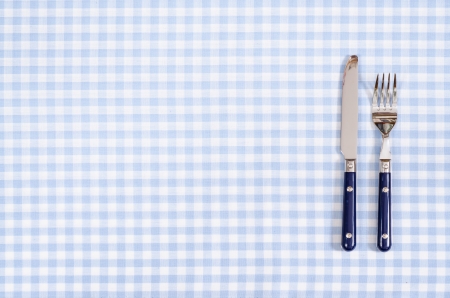 Blue knife and fork on a checkered table cloth with text spaceの写真素材