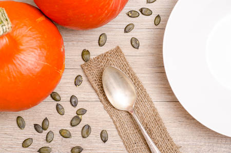 Dining table with pumpkins, seeds, plate and spoonの写真素材