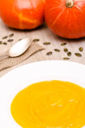 Pumpkin soup in a white plate in vertical formatの写真素材