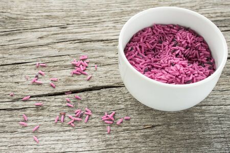 Bowl with pink raw rice on a wooden boardの写真素材