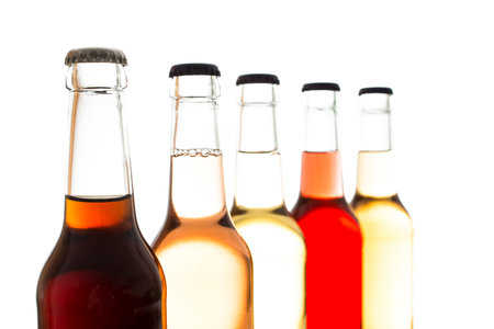 Cola and colorful lemonades in glass bottles in backlightの写真素材