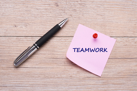 Word teamwork on pink sticky note with red pin and ballpoint penの写真素材