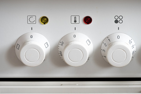 White control knobs at a electric oven with patinaの写真素材