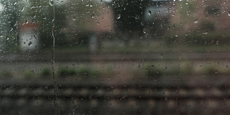 Drops of rain at a window with blurred rails in backgroundの写真素材