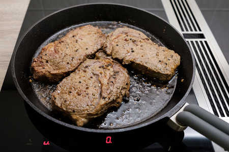 Marinated beef in a cast iron frying pan on induction stoveの写真素材