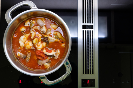 Octopus with tomatoes in a cooking pot on a stoveの写真素材