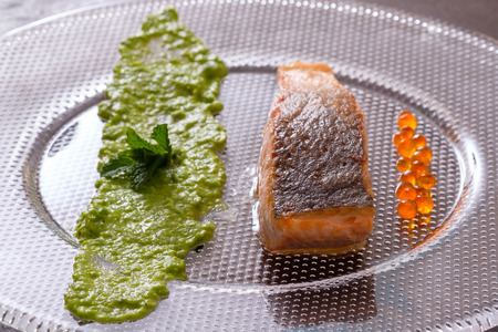 Roasted salmon fish with skin and mushy peas and caviar in backlightの写真素材