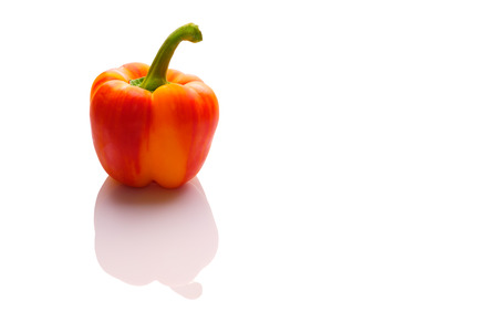 Red orange pepper with reflection on whiteの写真素材