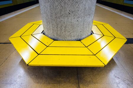 Yellow bench with round column at a train stopの写真素材