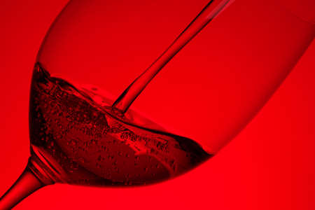 Red wine pouring in a bordeaux glass in back litの写真素材