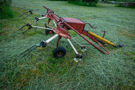 Red rotary rake trailer on a green meadowの写真素材