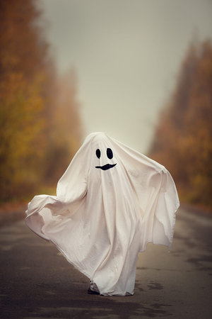 Funny kids Halloween concept, cute little kid in white costume, scary Halloween ghost in nature....