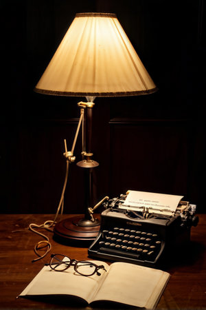 A classic vintage typewriter is illuminated by an antique lamp with its pages turned over; eyeglasses rest atop open papers nearby.の素材