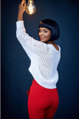 Spark of Creativity A Woman Illuminates Her Idea While Wearing Red Pants and Dark Blue Makeupの素材